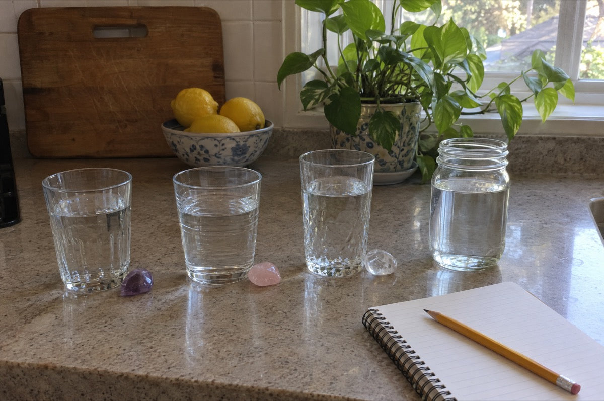 Glasses and a jar of water on a kitchen counter, each with a crystal resting beside it, the everyday habit that inspired Elixir2Go