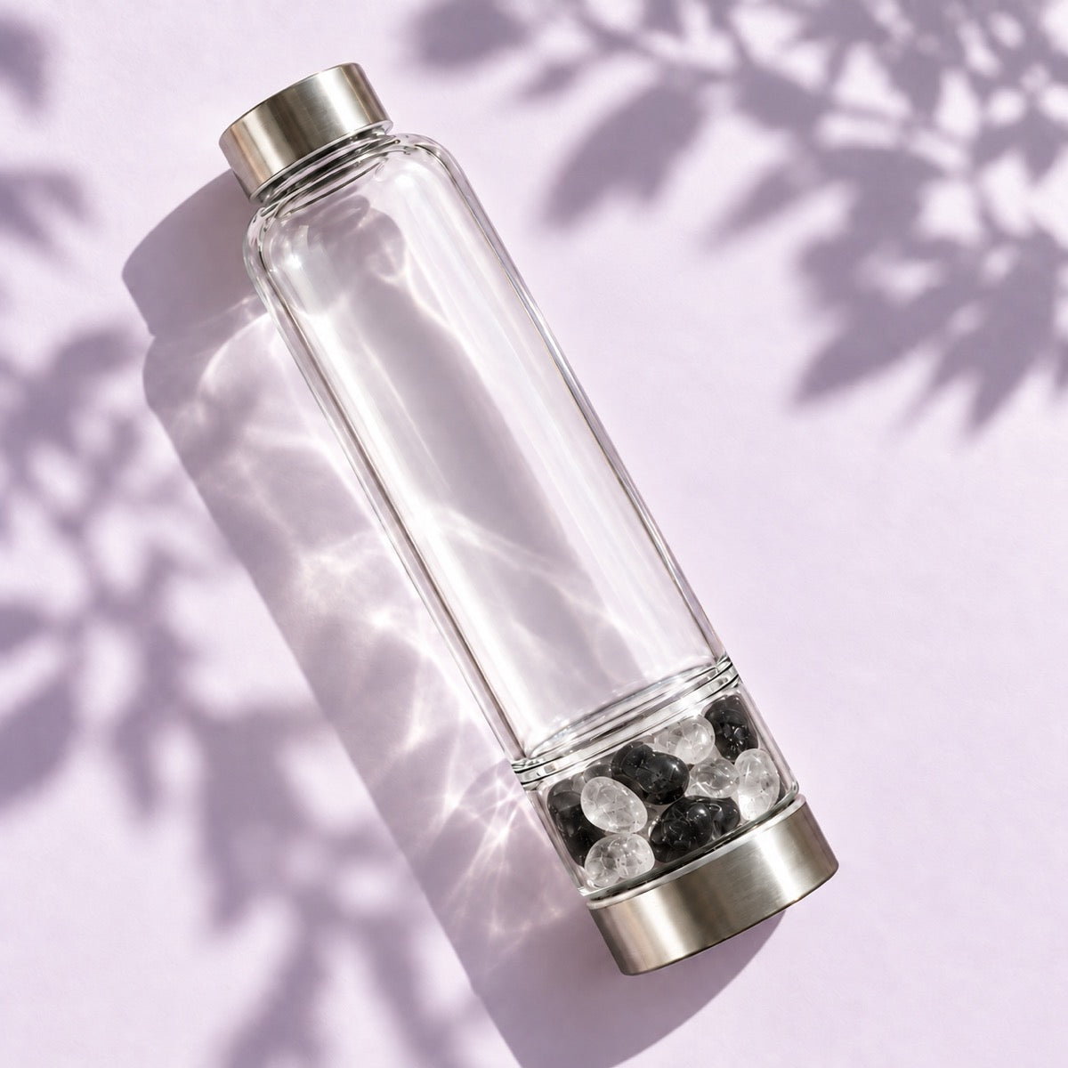 Elixir2Go crystal water bottle on a lilac surface with leaf shadows: clear water chamber above, Black Tourmaline and Clear Quartz in the separate lower chamber